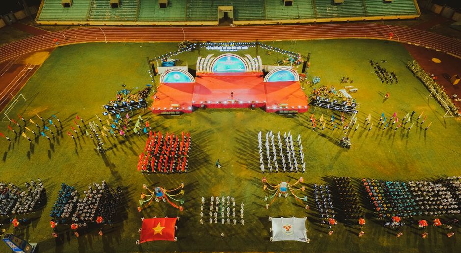A vibrant aerial shot of a sports event with organized groups and flags in a stadium.