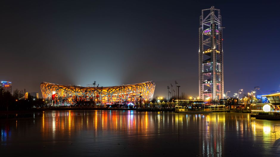 Stunning night shot of Beijing's Bird's Nest, reflecting vibrant city lights.