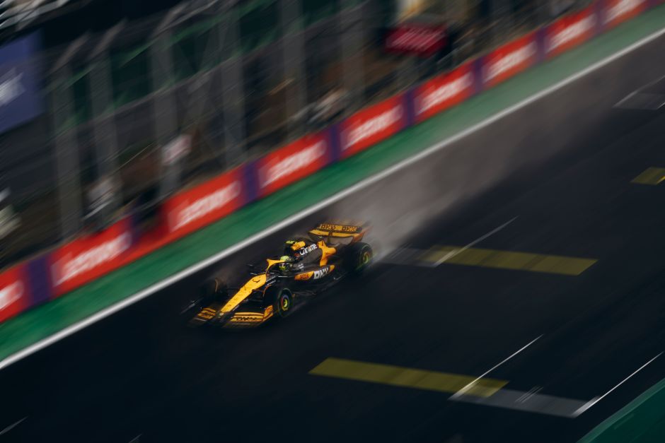 Dramatic capture of a high-speed race car on a rainy track, showcasing motion and speed.