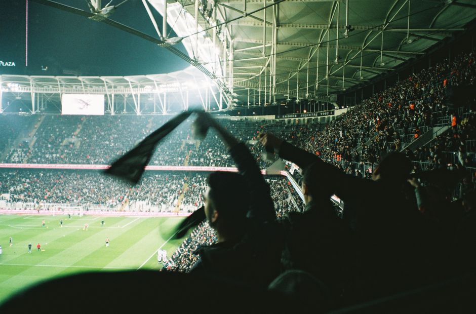 Exciting night soccer match with cheering fans in a brightly lit packed stadium.
