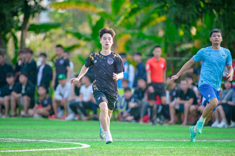 Dynamic scene of young adults playing soccer in Hà Nội, Vietnam.