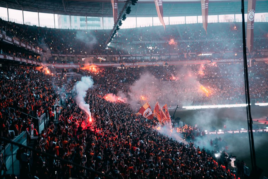 Exciting atmosphere with passionate fans and flares during a football match in İstanbul stadium.