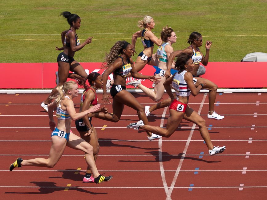 Empowering image of diverse female athletes sprinting in an outdoor track race.